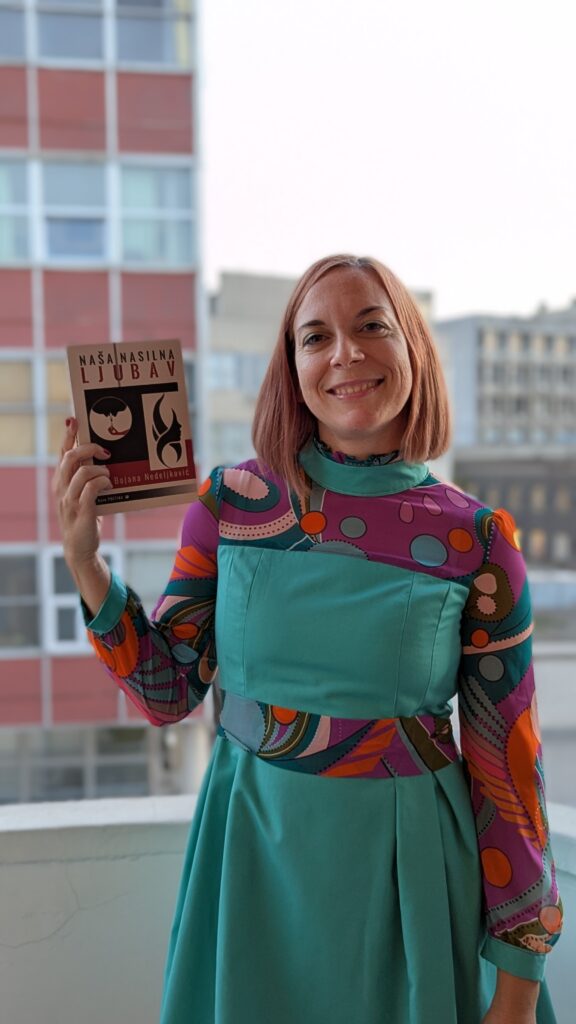 Bojana drži roman Naša nasilna ljubav u haljini koju je kreirala Zorana (gospođa Klara) na terasi prostora Centrala 24 u ulici Makedonska u Beogradu